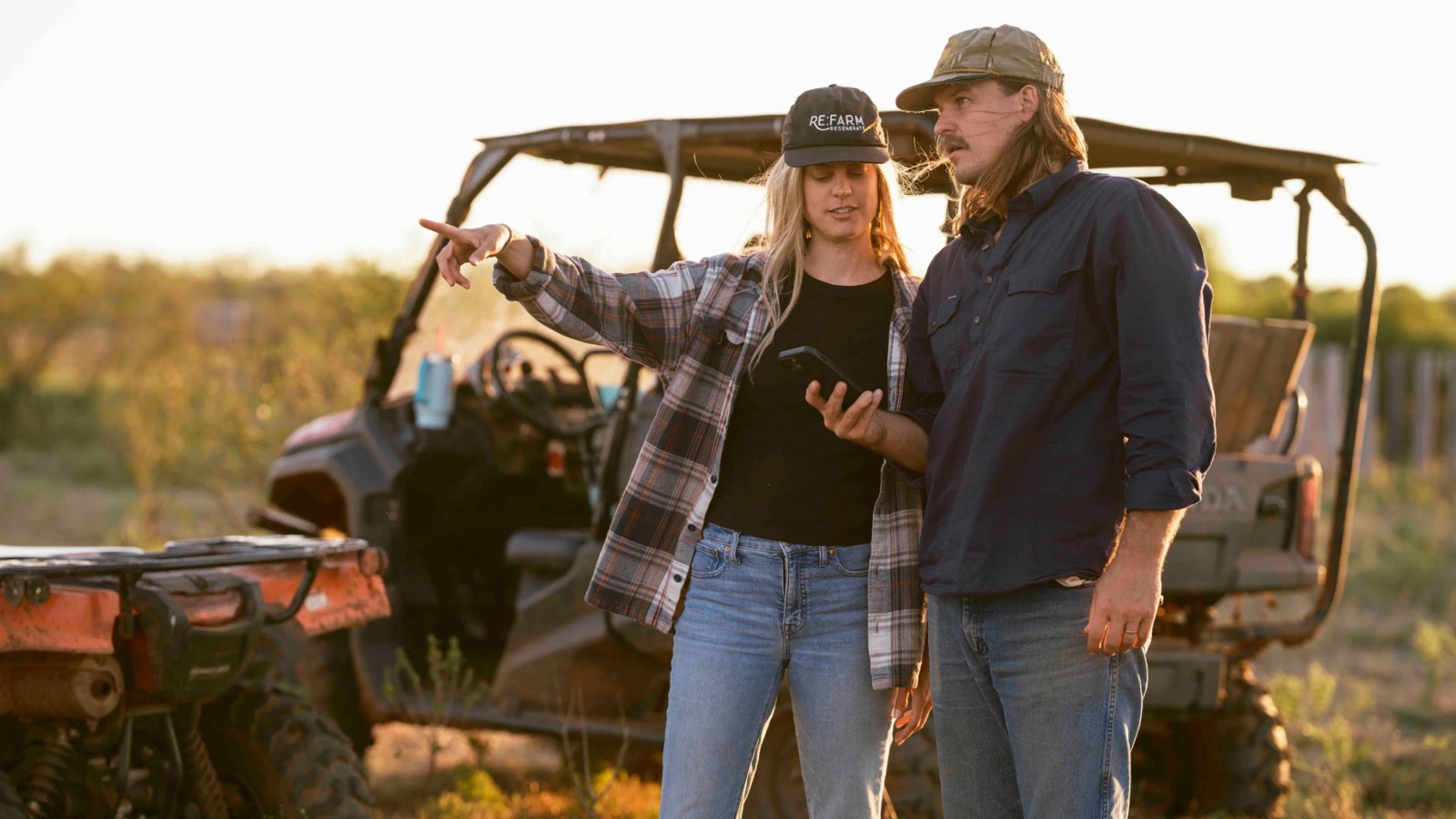 Zach and Kacie with the map on a phone, planning the next move from the side-by-side
